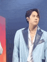 a man in a blue suit and a white shirt is standing on a stage .