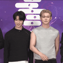 two men are standing next to each other in front of a purple background with a chinese symbol