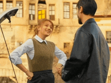 a man and woman are shaking hands in front of a building