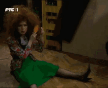 a woman with red hair is sitting on the floor holding a hot dog with ptc 1 written on the bottom