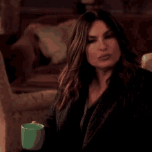a woman is sitting in a chair holding a green cup