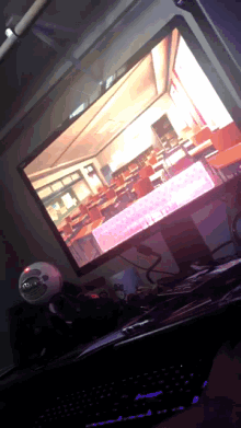 a computer monitor shows a classroom with empty desks and chairs and a keyboard