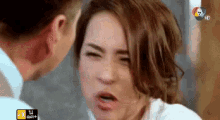 a woman is making a funny face while a man is looking at her .