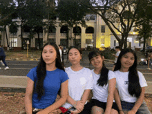 four girls are posing for a picture with one wearing a white chanel t-shirt