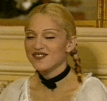 a woman wearing a braided pigtail and a black choker smiles