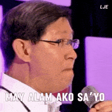 a man wearing glasses is holding a microphone and says may alam ako sa yo
