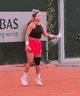 a woman is playing tennis on a court in front of a bas sign