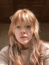 a young woman with long red hair and bangs is making a funny face .