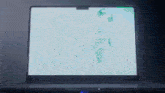 a laptop is open to a white screen with a few green spots on it