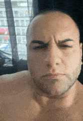 a shirtless man with a beard makes a funny face