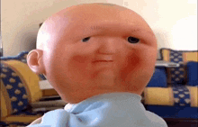 a close up of a baby doll with a bald head and a blue shirt .