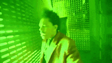 a man in a suit is standing in a room with a green light behind him .