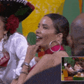 a woman wearing a sombrero and hoop earrings is smiling while sitting next to a man .