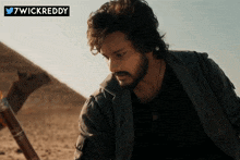 a man with a beard is standing in the desert with a 7wickreddy logo in the corner