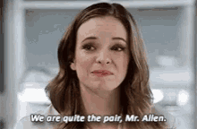 a woman is talking to a man in a room and says `` we are quite the pair , mr. allen . ''