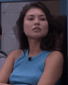 a woman in a blue tank top has a microphone on her shoulder