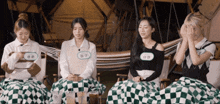 a group of girls sitting on blankets with one wearing a name tag that says ' ahn ' on it