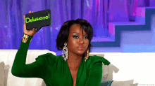 a woman in a green dress is holding a wallet that says " delusional "