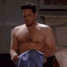 a shirtless man is holding a blue shirt in his hands