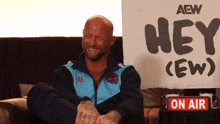 a man sits in front of a sign that says hey