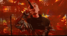 a man is singing into a microphone on stage in a dark room .