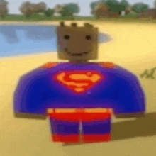 a lego man in a superman costume is standing on a sandy beach .