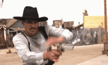 a man in a cowboy hat is pointing a gun at someone .