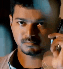 a man is talking on a cell phone and looking at the camera .