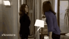 two women are standing next to each other in a living room with the words xnovelaira in the corner