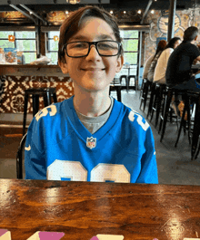 a boy wearing glasses and a blue nfl jersey