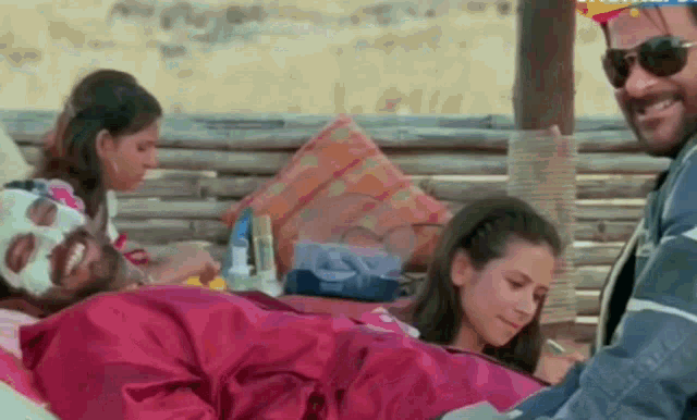 a man with a mask on his face is laying on a bed next to two women