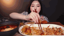 a woman eating food with chopsticks and a bowl of soup