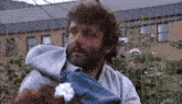 a man with a beard is holding a baby in his arms behind a fence