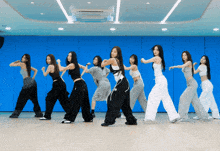 a group of women are dancing in a row in front of a blue wall