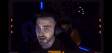a man in a yellow shirt is making a funny face while sitting in a dark room .