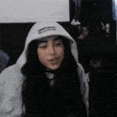 a woman is wearing a white hoodie and making a funny face .