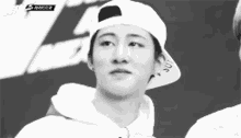 a black and white photo of a young man wearing a white baseball cap .