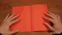 a person is holding a piece of red paper with the words made in animatica on the bottom right