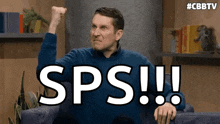 a man is sitting on a couch with his fist in the air and the word sps written on the screen