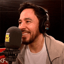 a man is wearing headphones and smiling in front of a microphone that says fm tty