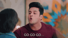a man in a maroon shirt is talking to a woman and says go go go