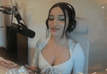 a woman wearing headphones is sitting in front of a microphone and smiling .