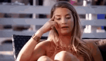 a woman is sitting on a couch with her hand on her forehead and thinking .