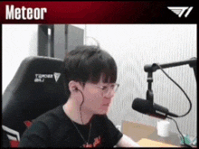 a man is sitting in front of a microphone with the word meteor above him