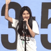 a young girl is standing in front of a microphone and waving her hand .