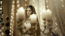 a woman in a white dress is standing in front of a candle holder