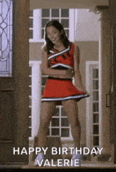 a cheerleader is standing in front of a door in a red skirt .