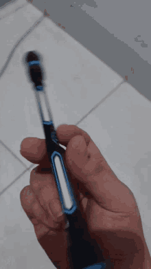 a person is holding a blue and black toothbrush in their right hand