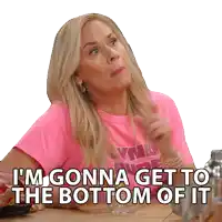 a woman in a pink shirt is sitting at a table and says i 'm gonna get to the bottom of it