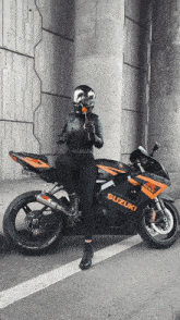 a woman sitting on a suzuki motorcycle with a helmet on